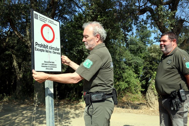 A rural officer in Les Gavarres putting up a sign that says only residents and emergency vehicles can go through (by Xavier Pi)